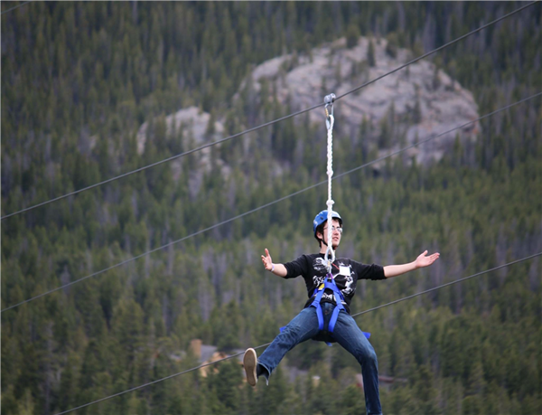 Teenage boy hanging from zipline in mountains Teenage boy hanging from zipline in mountains