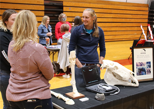 Veterinarian speaks with visitors at her table